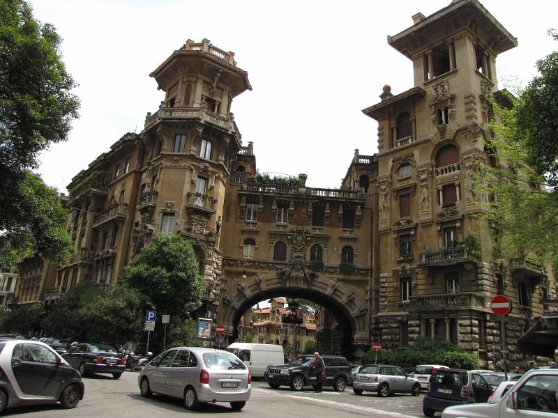 poort_naar_coppede quarter.jpg - Maandag 17 mei, de laatste dag in Rome. Tijdens een tramrit valt ons een kleine kerk op. De kerk valt uiteindelijk een beetje tegen, maar dat kan niet gezegd worden van de gebouwen met poort die er vlak achter liggen. Het blijkt de toegangspoort te zijn naar het  quartiere Coppedè.Coppedè staat voor Gino Coppedè, een italiaanse designer die aan het begin van de 20e eeuw deze buurt ontwierp.